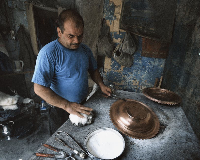 A skilled artisan polishes a copper tray in a traditional workshop, showcasing craftsmanship.