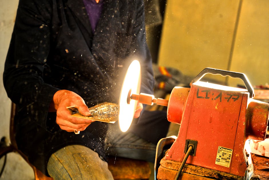 A craftsman polishes metal using an industrial grinder in a workshop, showcasing traditional skills.