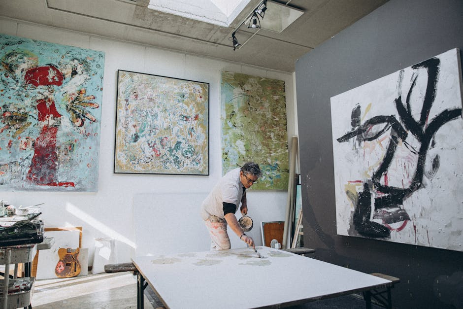 An artist working on a large canvas in a well-lit modern studio surrounded by abstract paintings.