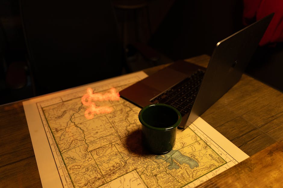 A cozy, dimly-lit workspace with a map, laptop, and coffee cup, evoking creativity and exploration.